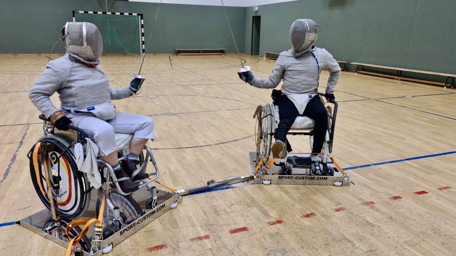 Wheelchair fencing — wide shot, two athletes on linked frames
